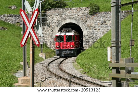 Red train out of train tunnel in Swiss, beautiful green grass