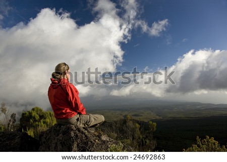 Woman in red Jacket doing Yoga and Meditation on the Mt Kilimanjaro mountain with Beautiful blue Sky