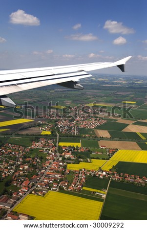 Airplane wing at settlement and land with beautiful blue sky.