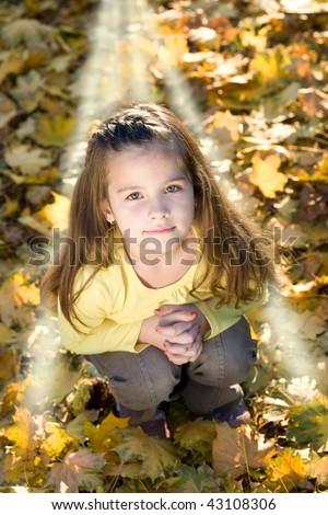 Portrait of little girl  prays to God in the autumn park. Mystic light.