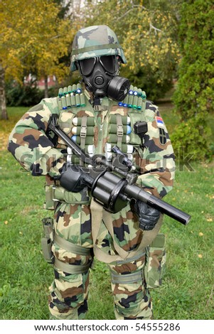 Soldier with gas mask in camouflage uniforms and full military equipment is ready for action.