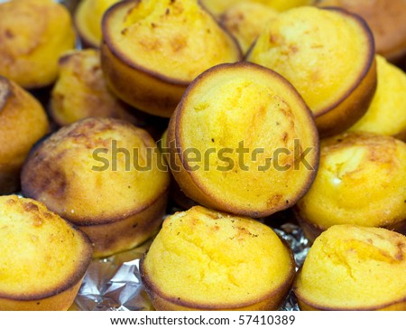 Close-up of golden corn muffins on plate with bowl of corn meal. Natural sunlight and shallow doff.