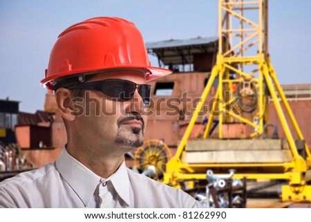 Big Manager, architect and supervisor oversees work on the construction site. In the background is a large crane. Selective focus, best focus is on the head Manager