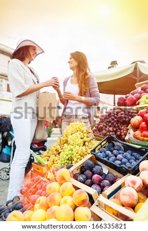 Happy Women Choosing A Fruit Outdoors In The Bio Market,Sunset Light. Focus On The Grape. Lens Flare