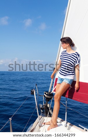 Beautiful young woman standing on the bow of a Sailboat, looking away. Copy space