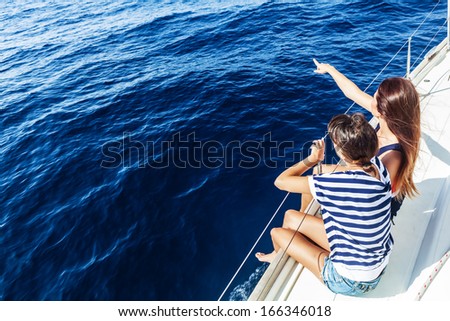 Happy women on the bow of a Sail Boat pointing to something. Copy space