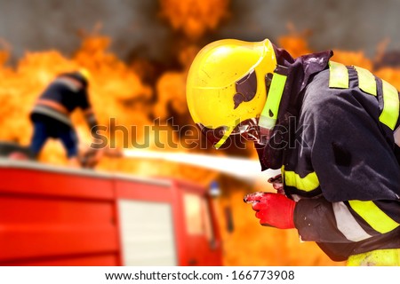 Fire fighter in an action. Fire truck and people are in a background. Shallow doff.
