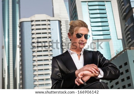 Businesswoman standing on the street and looking at her watch