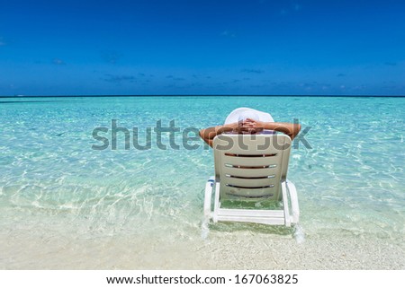 Young woman resting in deck chair at the tropical beach