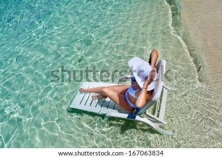 Beautiful woman resting in a deck chair at the tropical beach