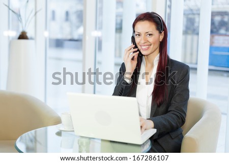 Woman with headphone talking and using a laptop computer