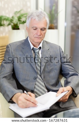 Senior businessman writing on paper