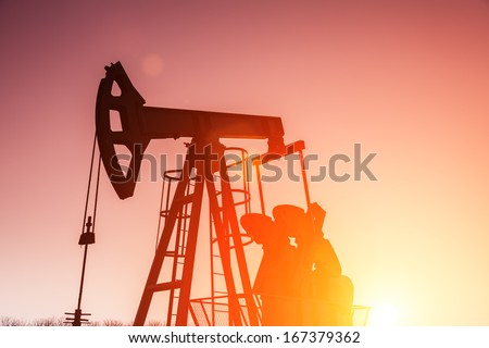Oil field pumpjack silhouette with setting sun. Lens Flare. See more images and video from this series and Refinery series.