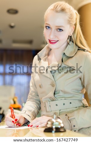 Attractive young women is checked out of the hotel and signs a hotel bill