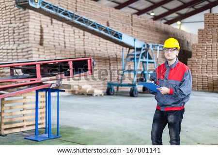 Engineer in the sugar factory. In a background are bags with sugar.