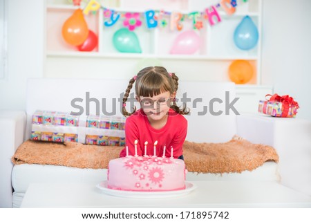 Little girl wishing something nice at the birthday party behind a Birthday cake. A little blurred motion and shallow doff.