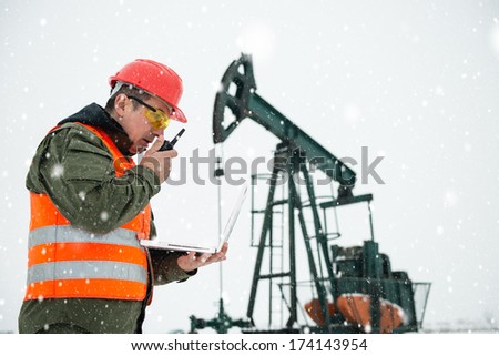 Oil Drill, field pump jack with snow storm and worker. Lens Flare. See more images and video from this series and Refinery series.