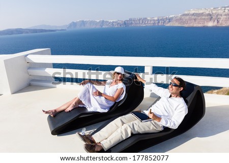 Elegant couple resting on the deck chair at the seaside terrace