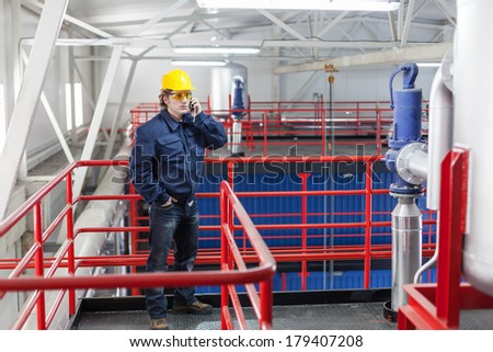 Worker in work wear using a mobile phone inside of the factory