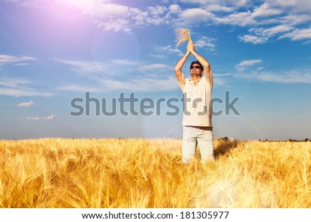 Satisfied man standing in the wheat field, flare light. The focus is on man\'s head. Copy space.