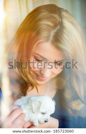Young girl with a puppy in her arms,through the window