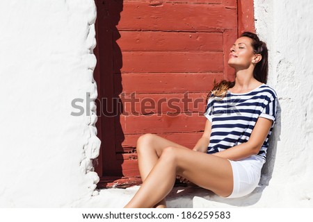 Young woman sitting in the front of the door, eyes closed, day dreaming.Copy space