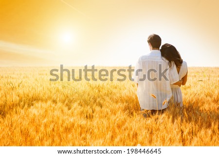 Rear view of young, couple in love in the wheat field..Sunset light, flare light, summer season, copy space