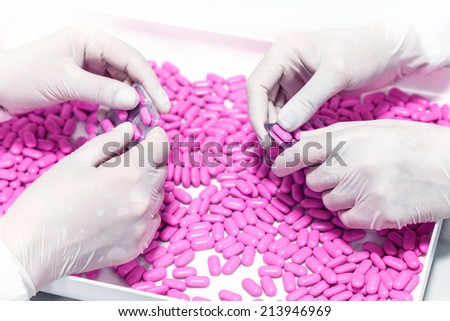 Female hands choosing, controlling the quality of a pills in a pharmaceutical factory.Unrecognizable people.Shallow doff.Macro, close up.