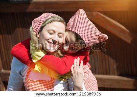 Mother and daughter gardening flowers in the back yard, daughter hugging her mother.Flare light