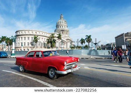 HAVANA, CUBA - OCTOBER 8, 2014: Old classic American red car rides in front of the Capitol. Before a new law issued on October 2011, Cubans could only trade cars that were on the road before 1959.