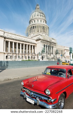 HAVANA, CUBA - OCTOBER 8, 2014: Old classic American red car rides in front of the Capitol. Before a new law issued on October 2011, Cubans could only trade cars that were on the road before 1959.
