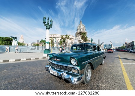 HAVANA, CUBA - OCTOBER 8, 2014: Old classic American green car rides in front of the Capitol. Before a new law issued on October 2011, Cubans could only trade cars that were on the road before 1959.