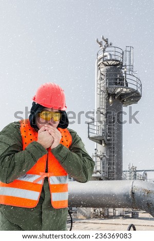 Worker at the cold oil field , natural gas storage in the background.Refinery, oil and natural gas, wintertime