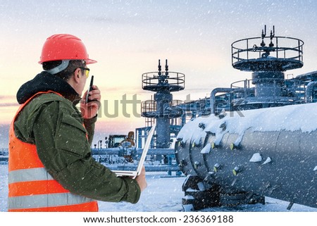 Worker at the oil field , natural gas storage in the background.Refinery , oil and natural gas