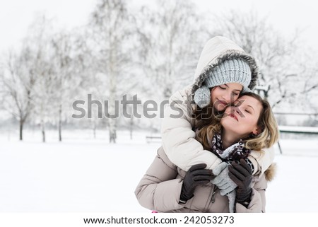 Mother and daughter hugging outdoors in the wintry landscape.Copy space
