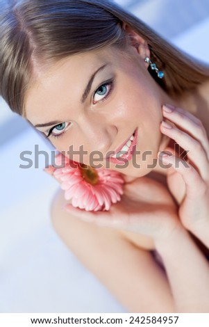 Portrait of beautiful, young, blonde woman with a pink Gerber daisy flower, head shot