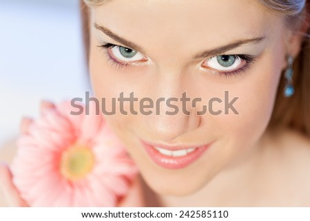 Portrait of beautiful, young, blonde woman with a pink Gerber daisy flower, head shot