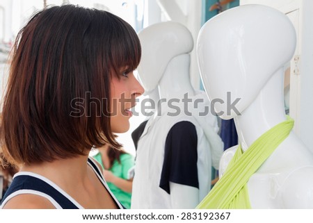 Funny, young woman standing face to face with mannequin on the street