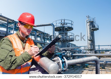 Engineer writing on the paper in front of the natural gas pipes.Refinery, gas and oil