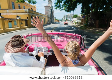 Rear view of happy friends enjoying in the convertible car drive through Havana