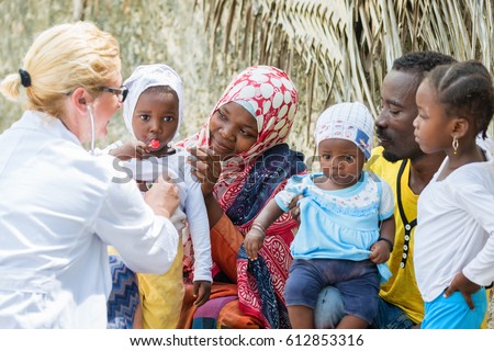 Female Caucasian doctor listening heart beat and breathing of little African girl with stethoscope, family looking medical exam