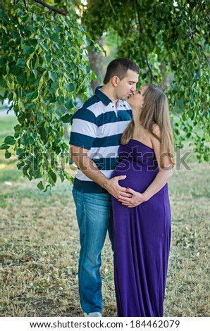 Portrait of a happy, young man touching his pregnant wife\'s belly