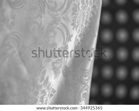 White linen flower patterned hanging in front of black and white polka dot pattern.