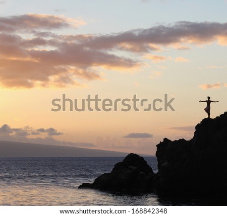 An inspiring silhouette of a man standing on rocks at the ocean
