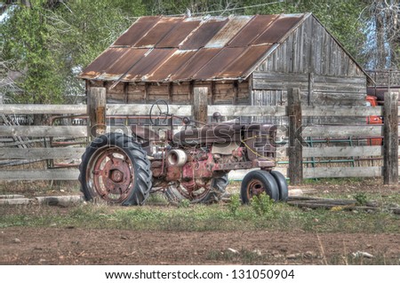 An old tractor, though retired, sits in the barn yard as an icon of the good ole days. \