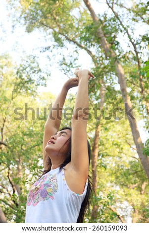 woman standing with arms open and eyes closed to breath the clean air from a spring forest