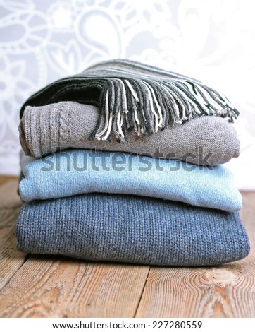 Pile of warm wool clothing lying on a wooden table