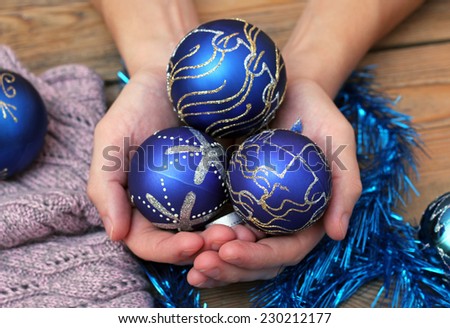 Man hands holding blue christmas balls under wooden table and wool scarf