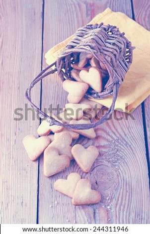 Love, happy, home, food, still life concept. Handmade heart cookies for Valentine\'s day in a basket lying on a wooden table. Selective focus. Vintage style, toned image
