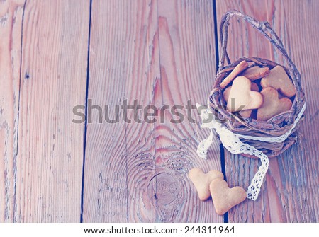 Holidays, love, food and drink concept. Handmade heart cookies for Valentine\'s day in a basket on a wooden table. Vintage style, toned image. Selective focus, copy space background.